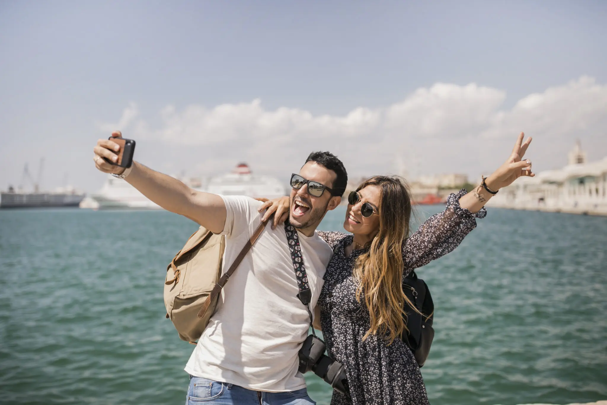 woman-making-peace-sign-with-her-boyfriend-taking-selfie-mobile turistas internacionais