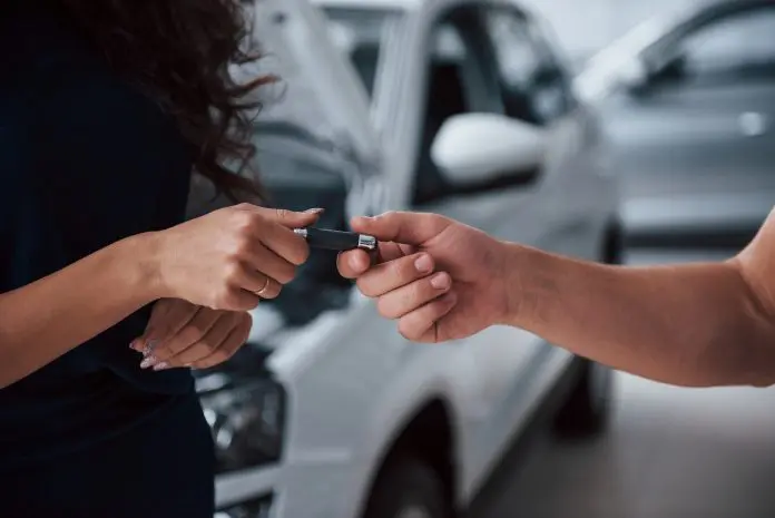 Side view. Woman in the auto salon with employee taking her repaired car back Rentcars parcerias