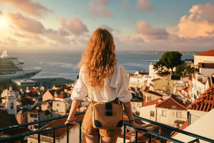 young-female-standing-platform-surrounded-by-fences-observing-lisbon-daytime-portugal europa viagens