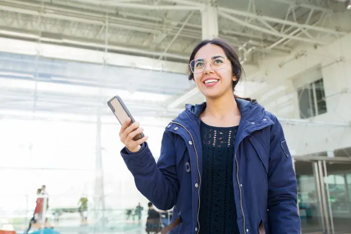 Smiling positive girl using phone outdoors Latam pass Juspay