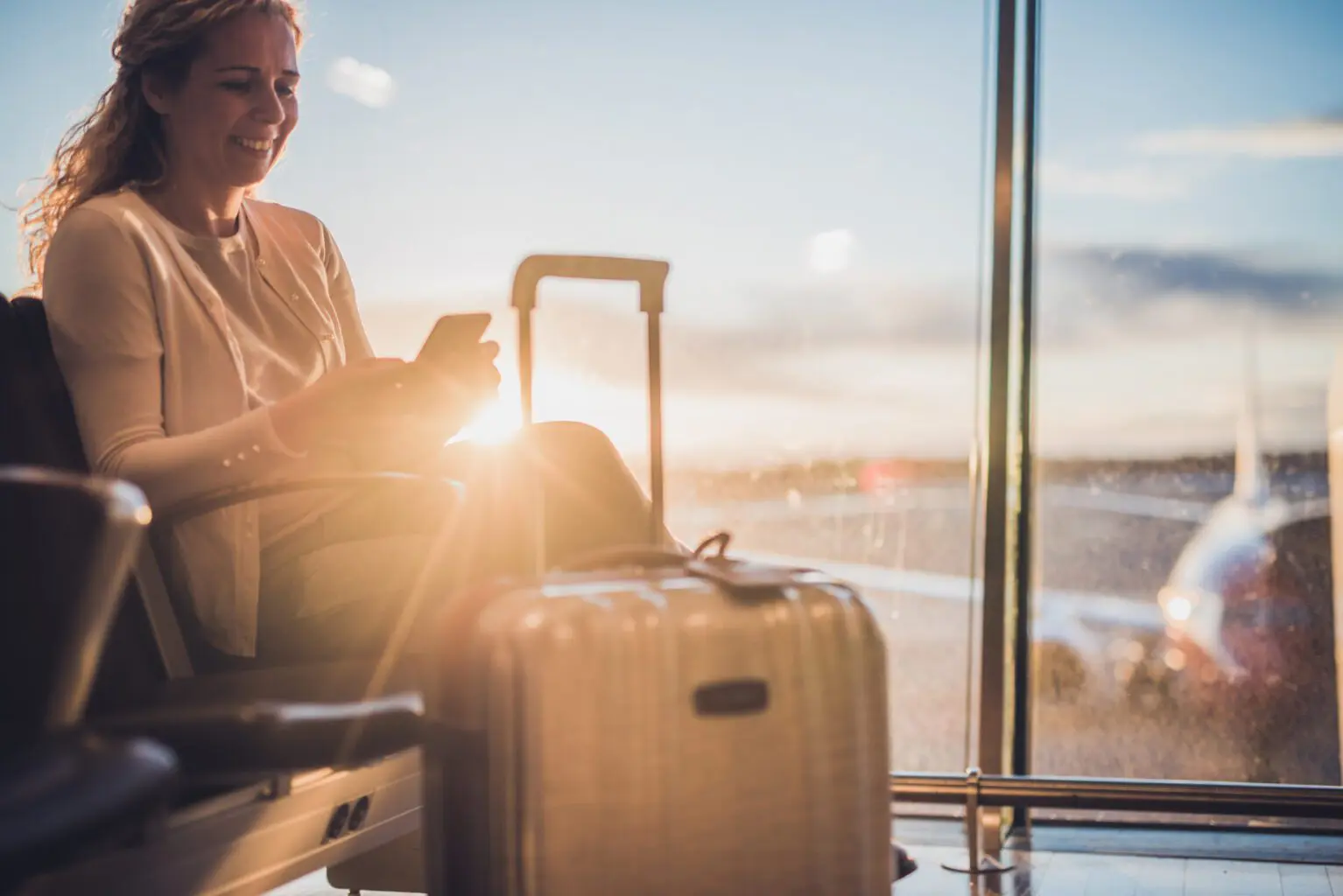 young-female-passenger-at-airport-using-smartphone-high-res