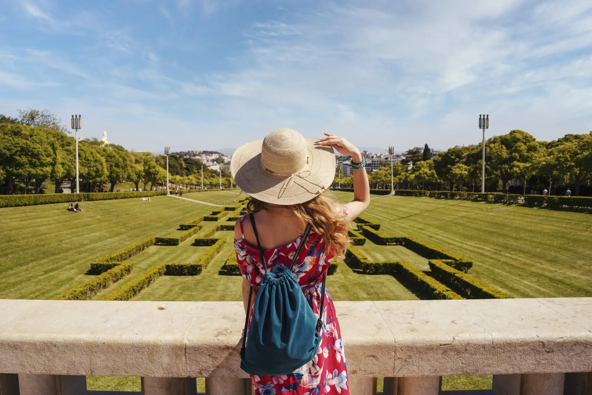 Young female tourist in a red floral dress in The Eduardo VII Park under the sunlight in Portugal turismo experiência