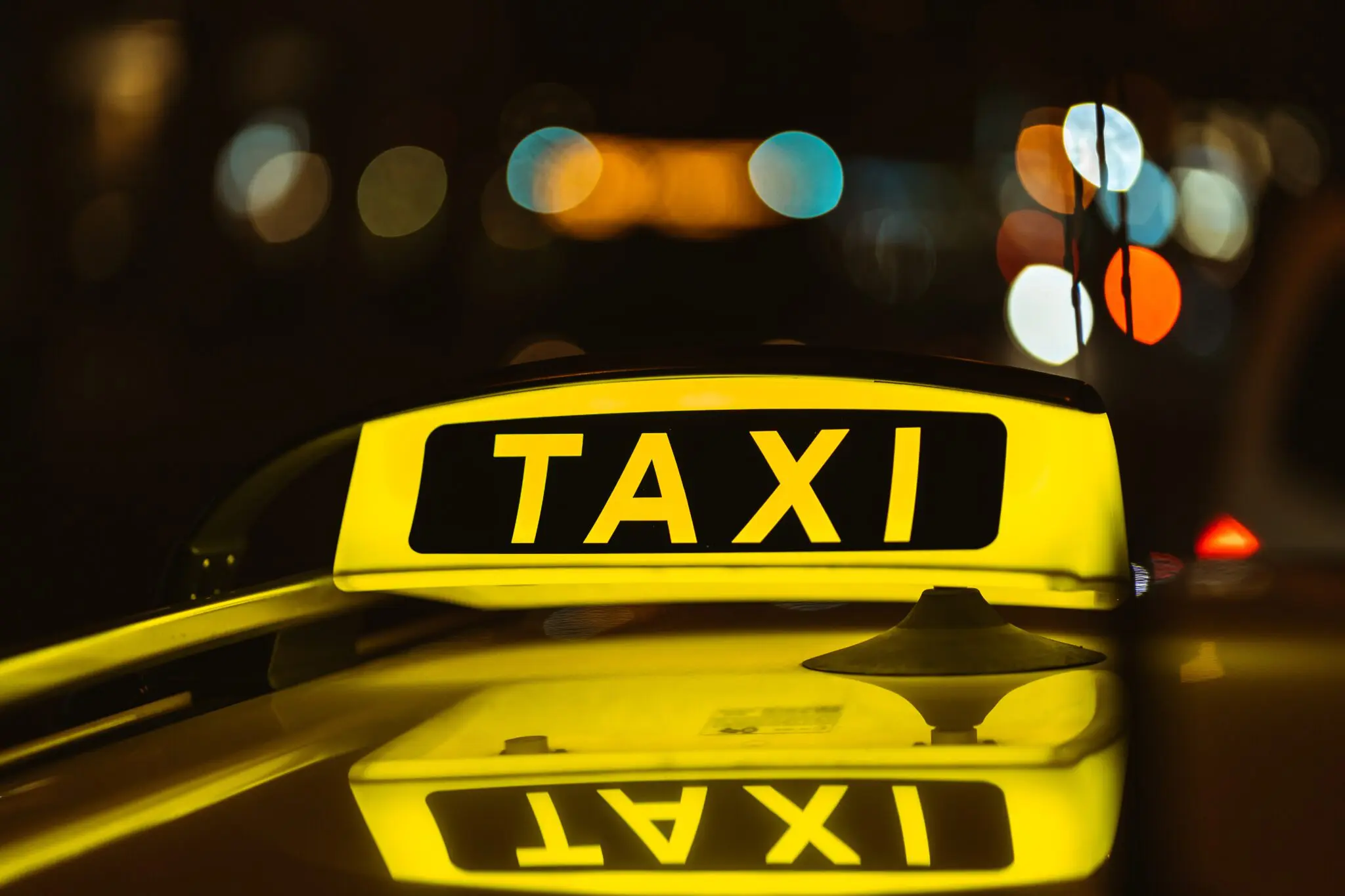 Black and yellow sign of Taxi at night placed on top of a car táxi rio janeiro