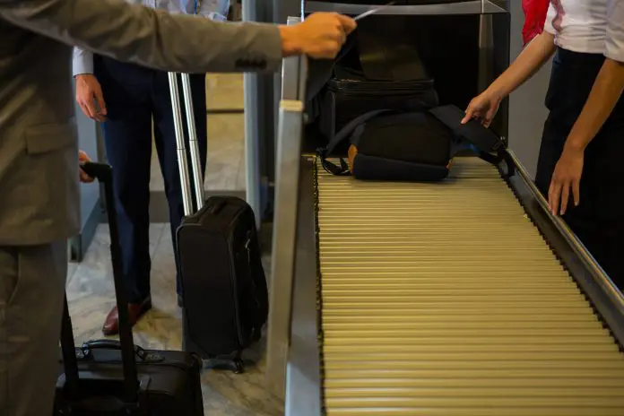 Female staff checking passengers luggage on conveyor belt in airport extravio bagagem malas extraviadas