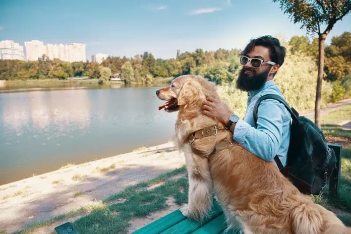 Young man sitting with his dog on the chair in the park turismo pet friendly