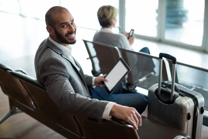 smiling-businessman-with-digital-tablet-sitting-waiting-area